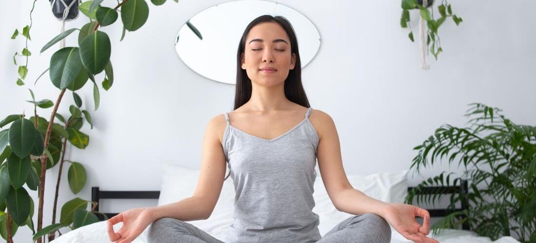 how to create a meditation room woman meditating in bedroom