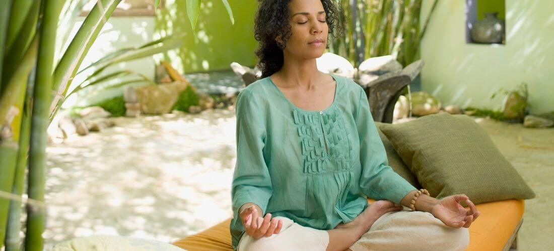 woman meditating in her outdoor meditation space